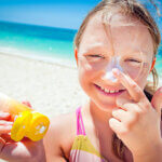 Photo d'une petite fille mettant de la crème solaire